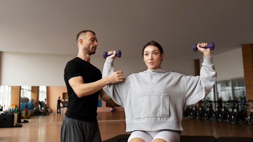 Coach correcting a client's shoulder position during a dumbbell press as part of science-based strength training in Dubai