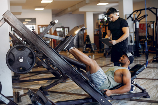 Lamann360 coach tracking a client's progress during a leg press strength training session in Dubai